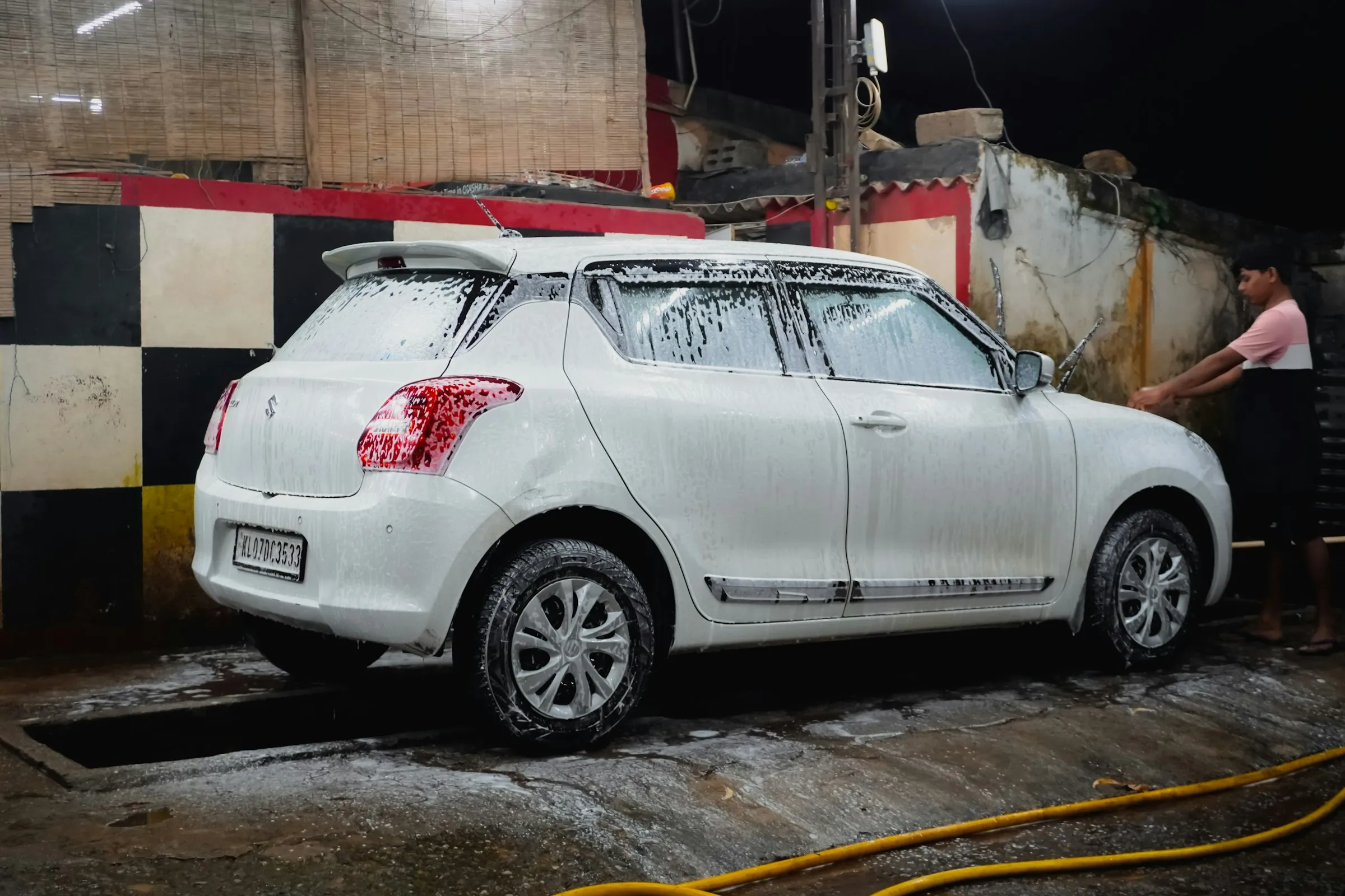 Operario lavando un auto cubierto de espuma fuera del taller