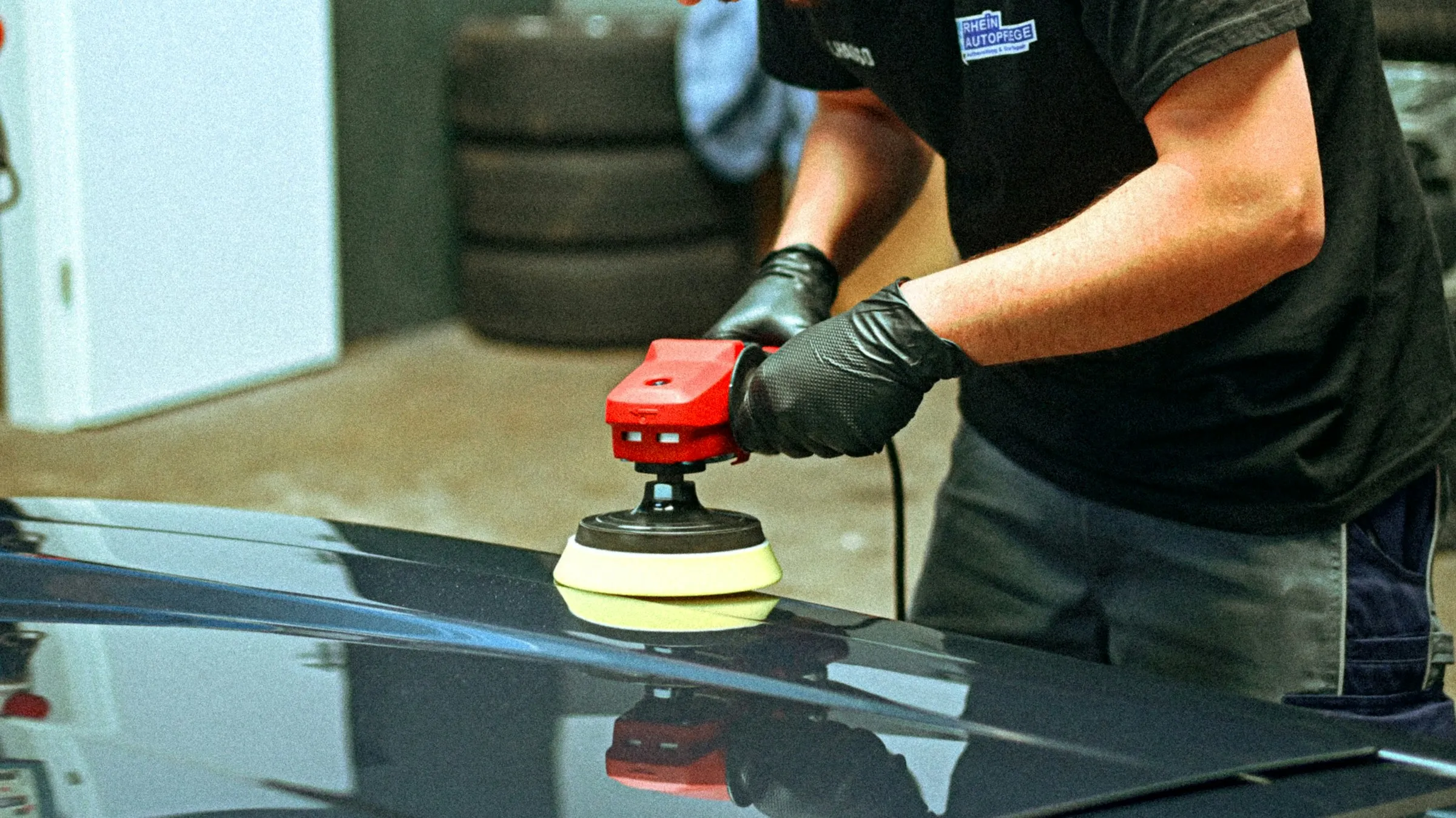 Pulidora eléctrica trabajando sobre la pintura de un auto oscuro